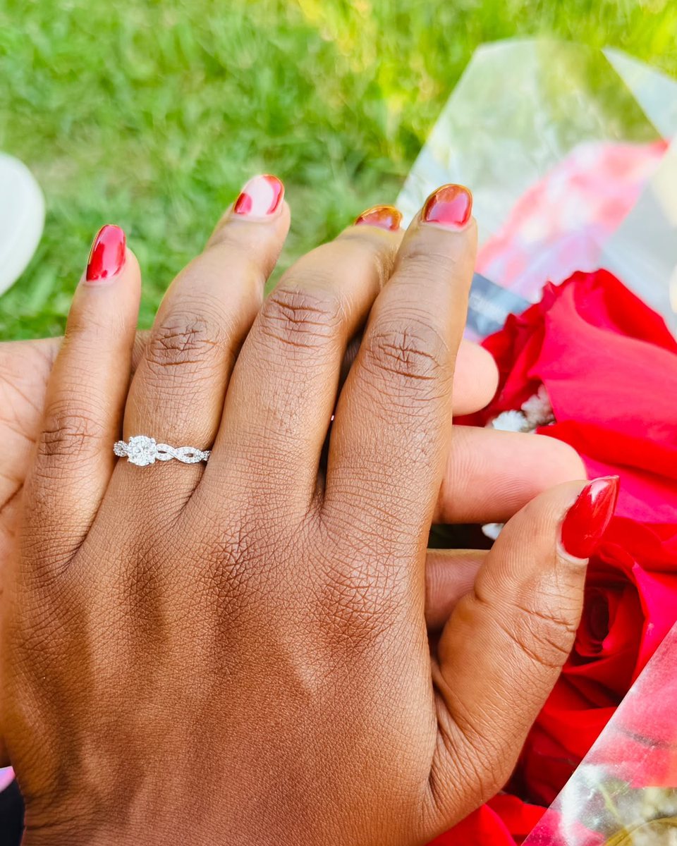 Gamu's hand with her engagement ring, resting on red roses